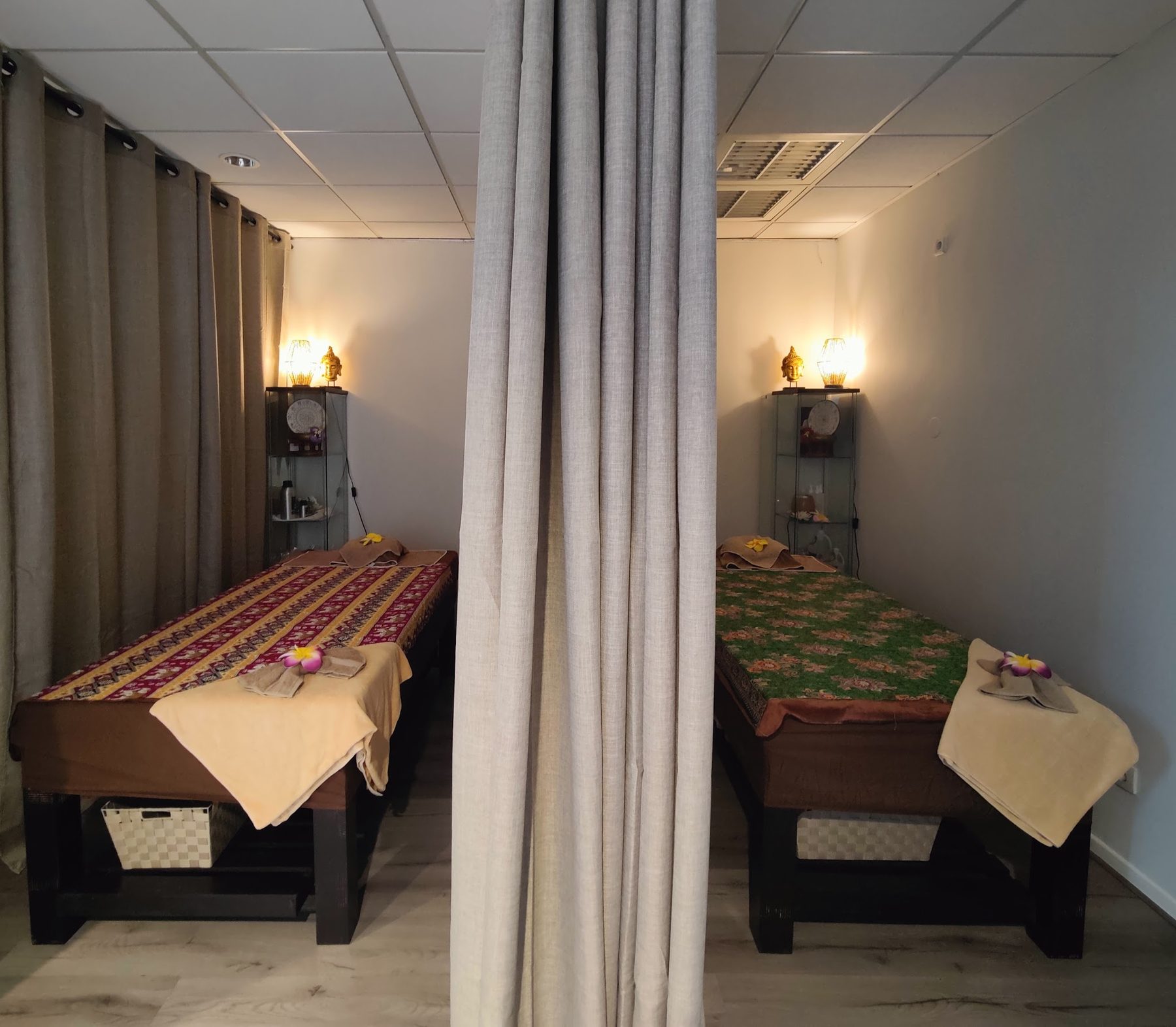 Twee massagetafels naast elkaar, gescheiden door een linnen gordijn